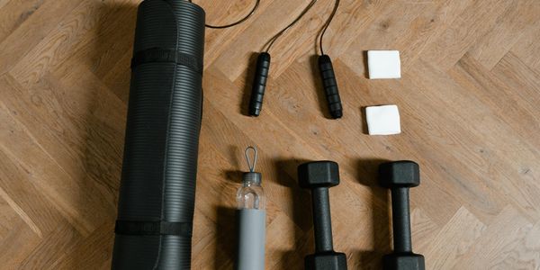 Two black dumbbells lying on a wooden floor.